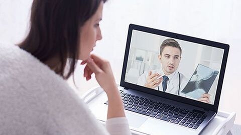 Patientin spricht über ein Notebook mit dem Arzt und sieht ihr Röntgenbild